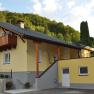Yellow house with balcony and sign 'Apart Dirndltal' in front of a wooded hill.
