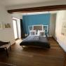 Modern bedroom with wooden floor, blue accent on the wall, double bed and rattan chair.