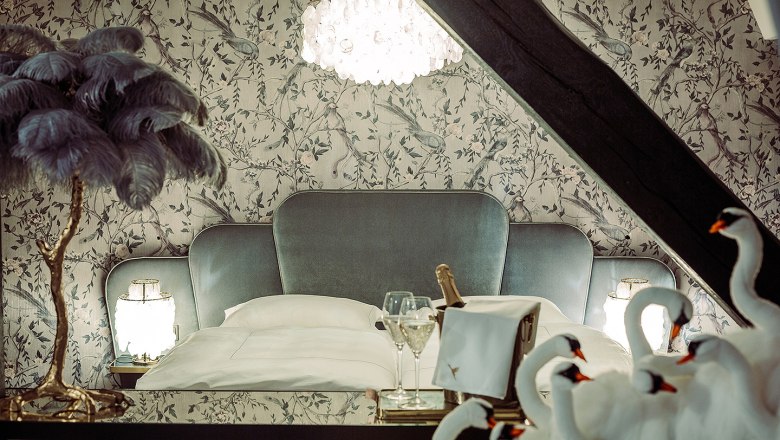 Elegant bedroom with luxurious bed, chandelier and decorative swans.