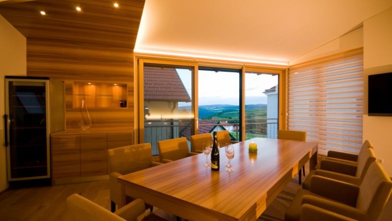 Modern tasting room with wooden table, chairs and panoramic window overlooking the countryside.