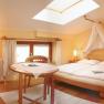 Comfortable hotel room with double bed, table and skylight.