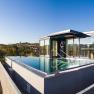 Rooftop pool with glass walls on a modern building surrounded by countryside.