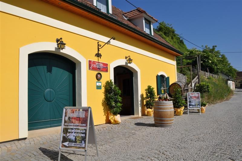 Yellow building with wine cellar and advertising boards in front of it.