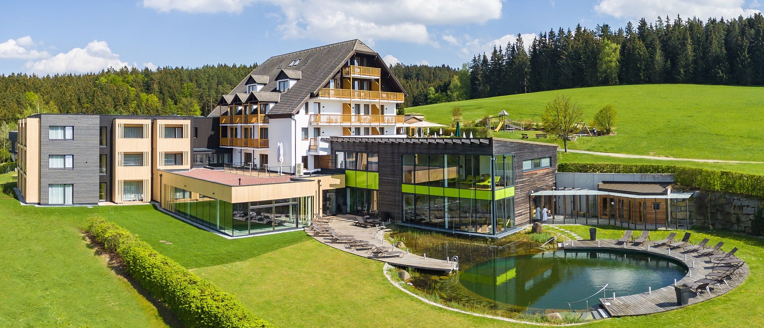 Hotel Schwarz Alm with modern design, surrounded by green landscape and forest.