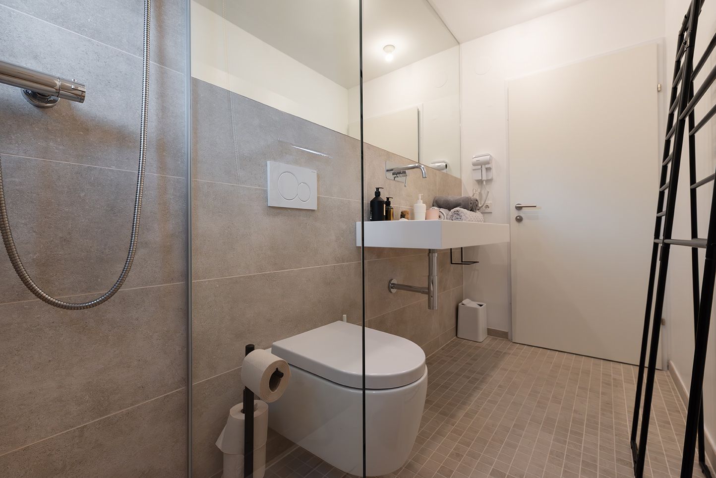 Modern bathroom with glass shower, washbasin and toilet.