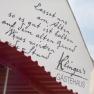 Façade of Klinger's guest house with handwritten inscription and red canopy.