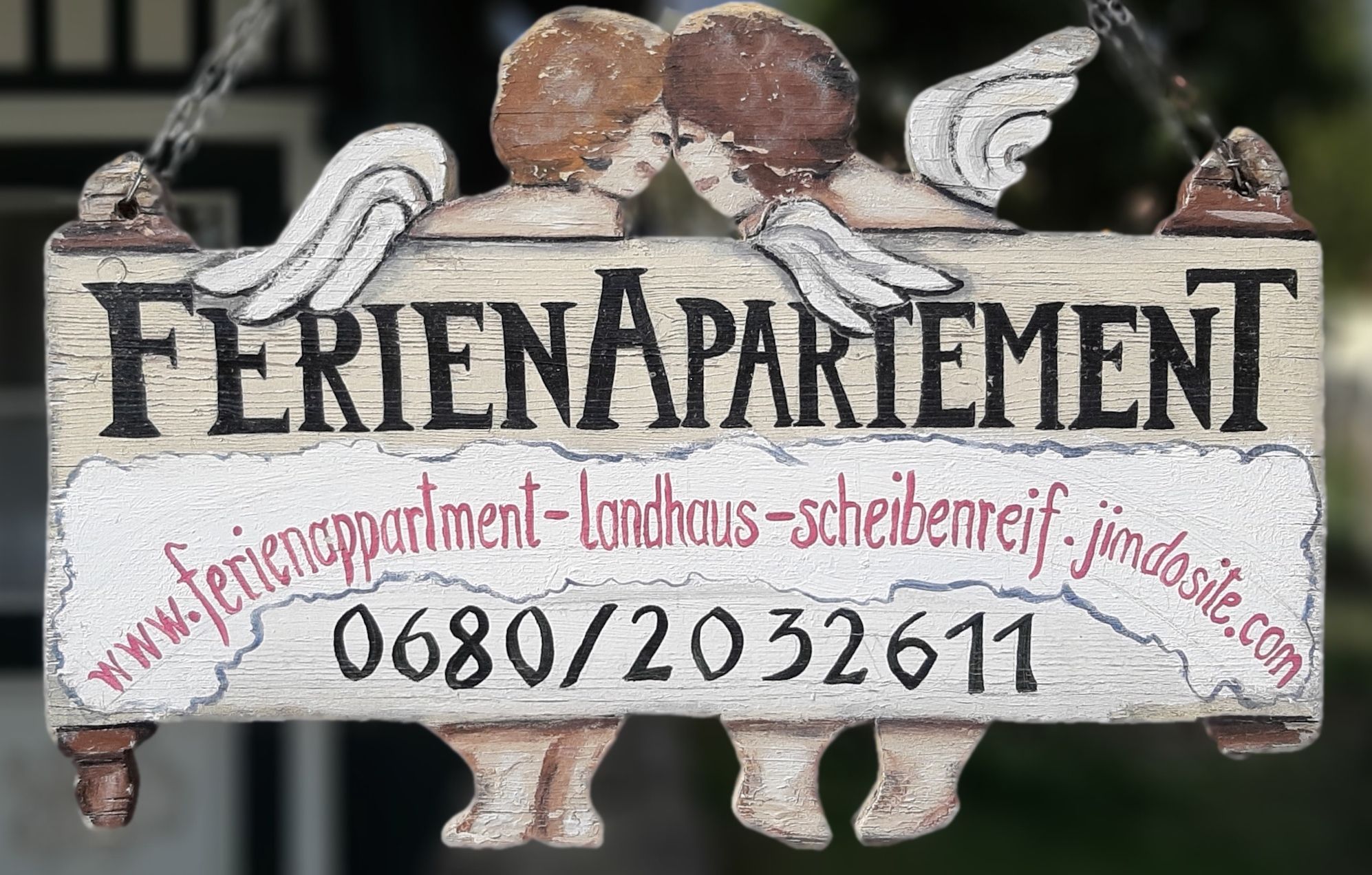 Wooden sign with the inscription 'Ferienapartement' and two angels.