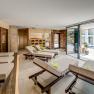 Modern relaxation area with loungers and a view of a pool through large windows.