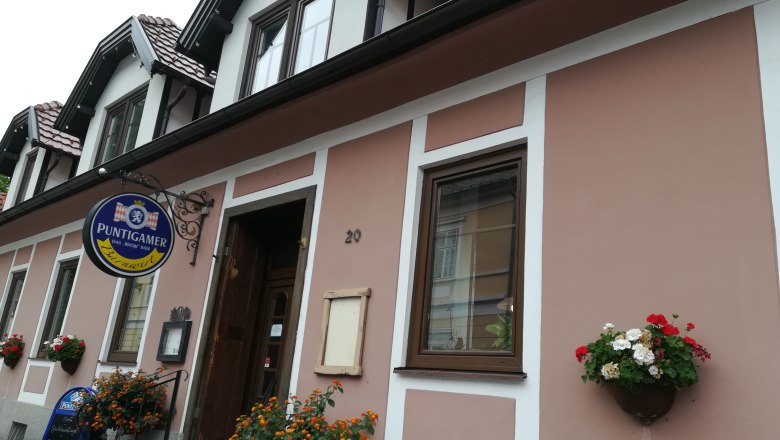 Exterior view of a building with 'Puntigamer' sign and floral decoration.