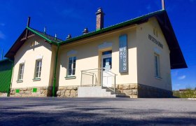 Exterior view of a small museum building with a yellow façade and green accents.