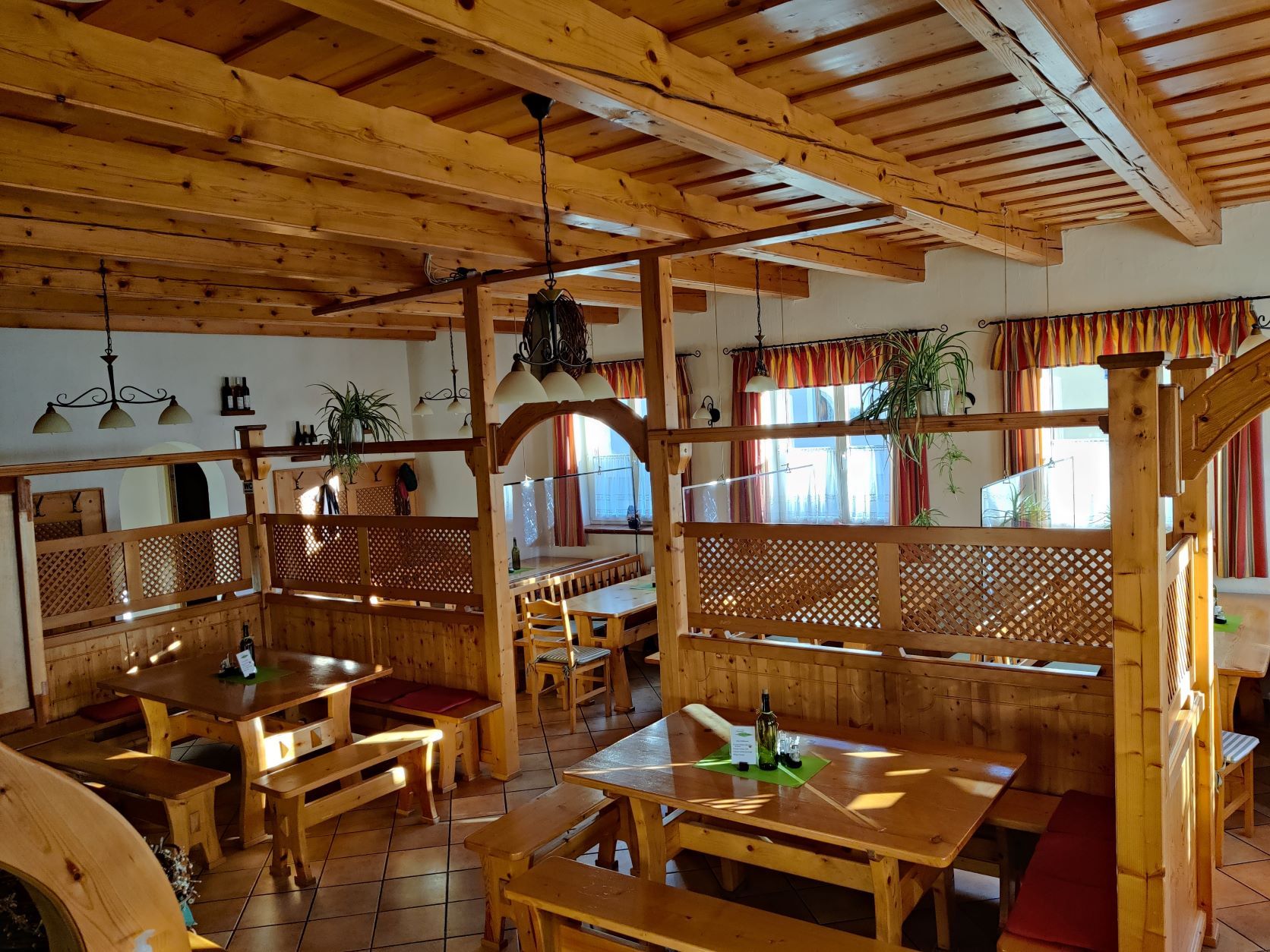 Interior view of a rustic wine tavern with wooden furniture and plants.