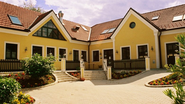 Yellow building with red tiled roofs and garden.