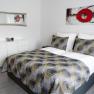 Modern bedroom with double bed, abstract artwork and mirror.
