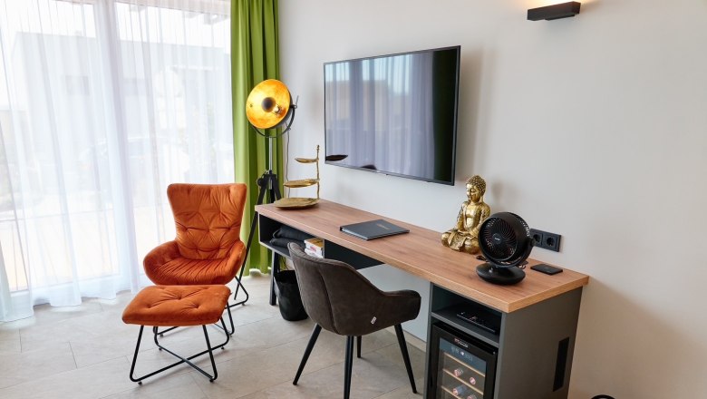Living room with armchair, desk, Buddha statue and TV.