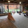 Interior view of a play barn with toy cars, wooden blocks and two children in winter clothing.