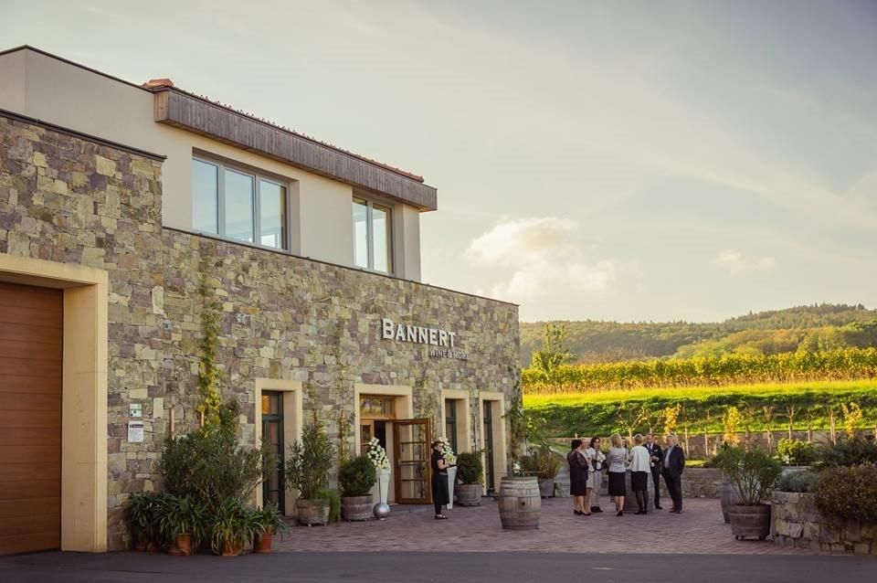 Bannert winery with people in front of the building and vineyards in the background.