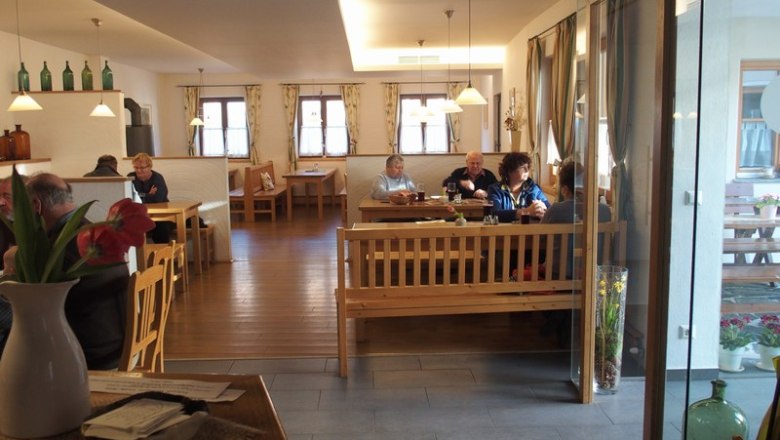 Interior view of a cozy wine tavern with wooden furniture and guests at tables.