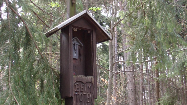 Wooden cross with Christ figure in the forest, inscribed with 'Beim Toten Mann'.