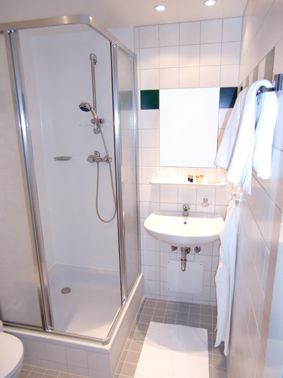Small bathroom with shower, washbasin and towels.