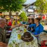 Group of people clinking glasses in a restaurant garden.