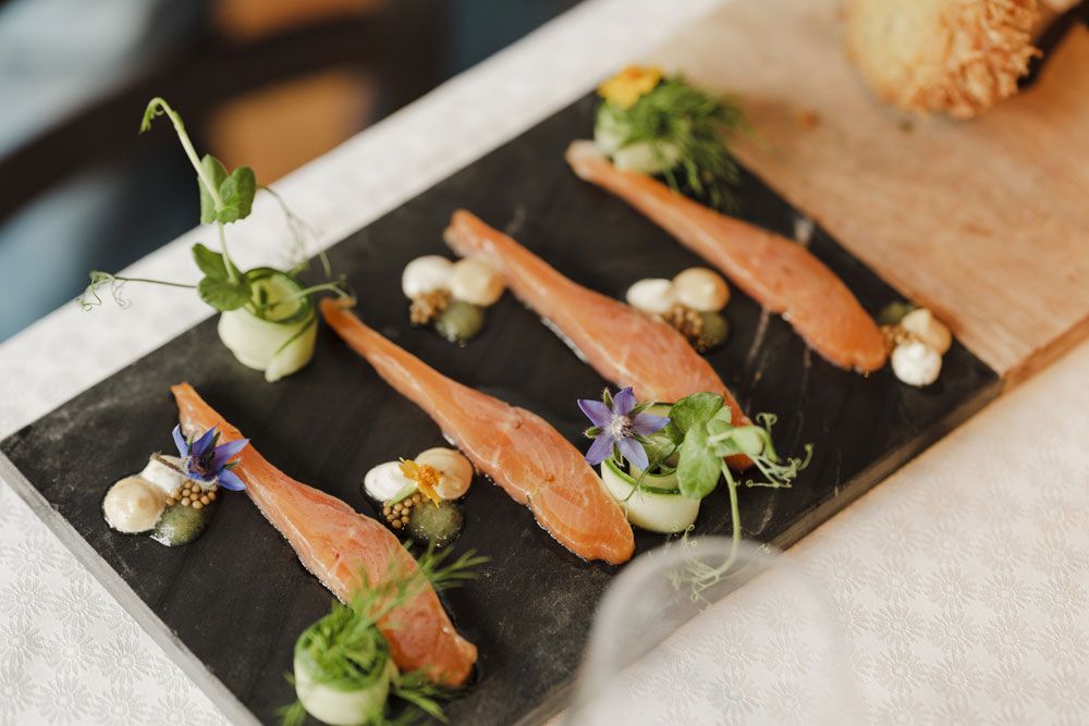 Gourmet dish with salmon, herbs and flowers served on a slate plate.