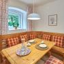 Cozy dining area with wooden table, corner bench and checkered cushions.