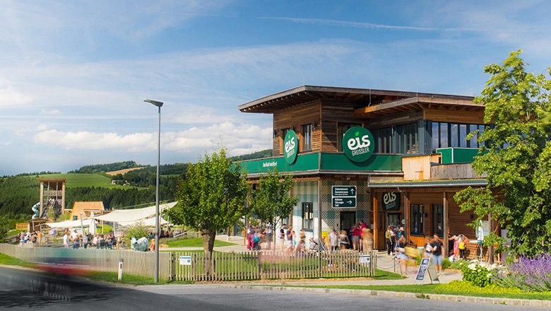 Building of the Eis-Greissler Welt with trees and visitors and view of the adventure park.