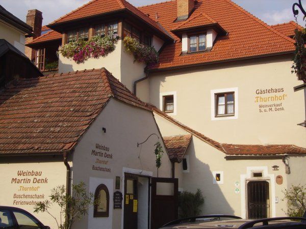 Exterior view of a traditional building with red tiled roofs and flower boxes on the windows.