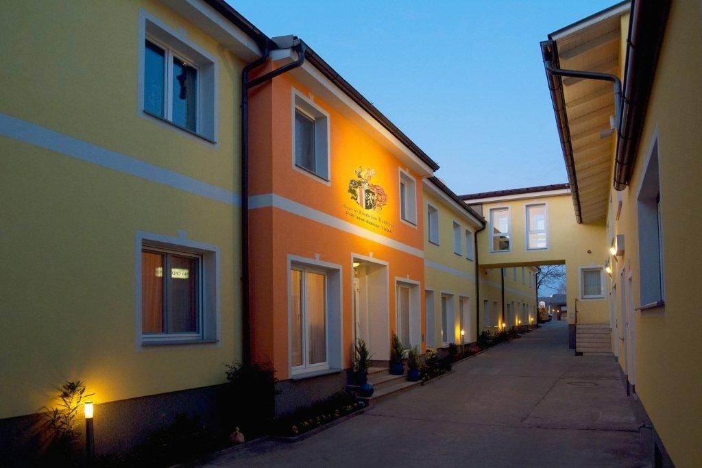 Exterior view of the Hotel Radlinger at dusk with yellow and orange facades.