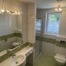 Modern bathroom with green tiles, shower, washbasin and WC.