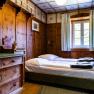 Rustic double room with wooden walls, a bed and a chest of drawers.
