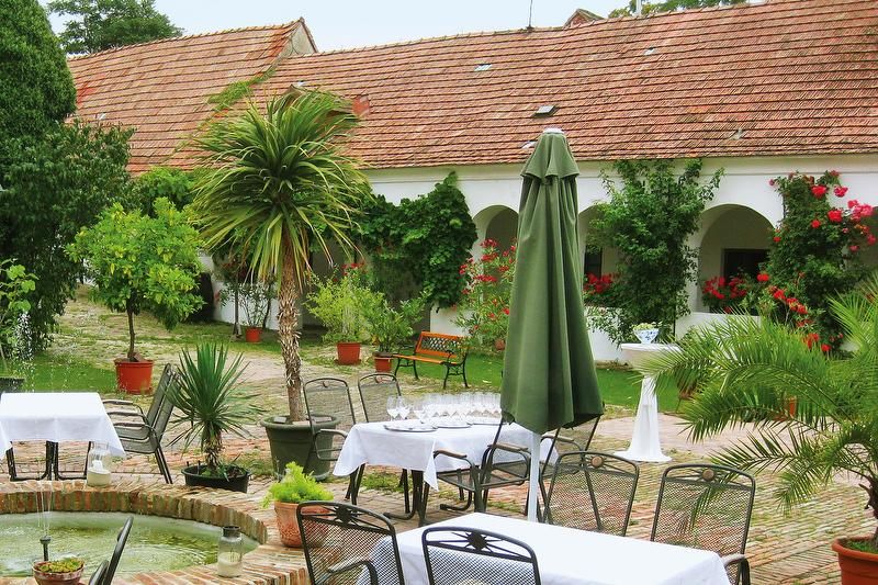 An idyllic courtyard with tables, chairs, plants and a fountain.