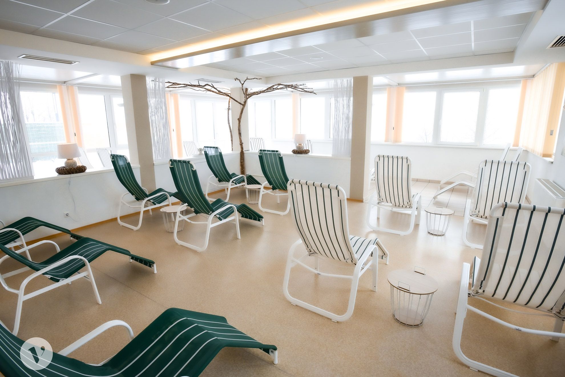 A bright relaxation area with several green deckchairs and small tables.