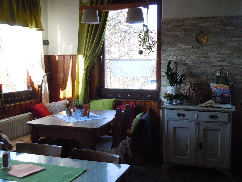Cozy corner in a room with wooden table, cushions and plants.