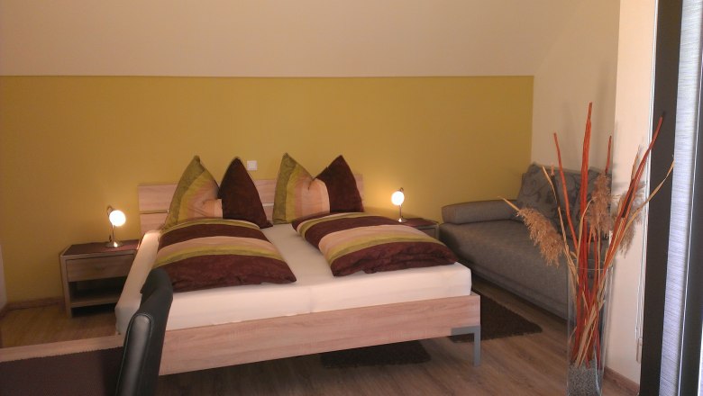 Cozy bedroom with double bed, sofa and decoration.