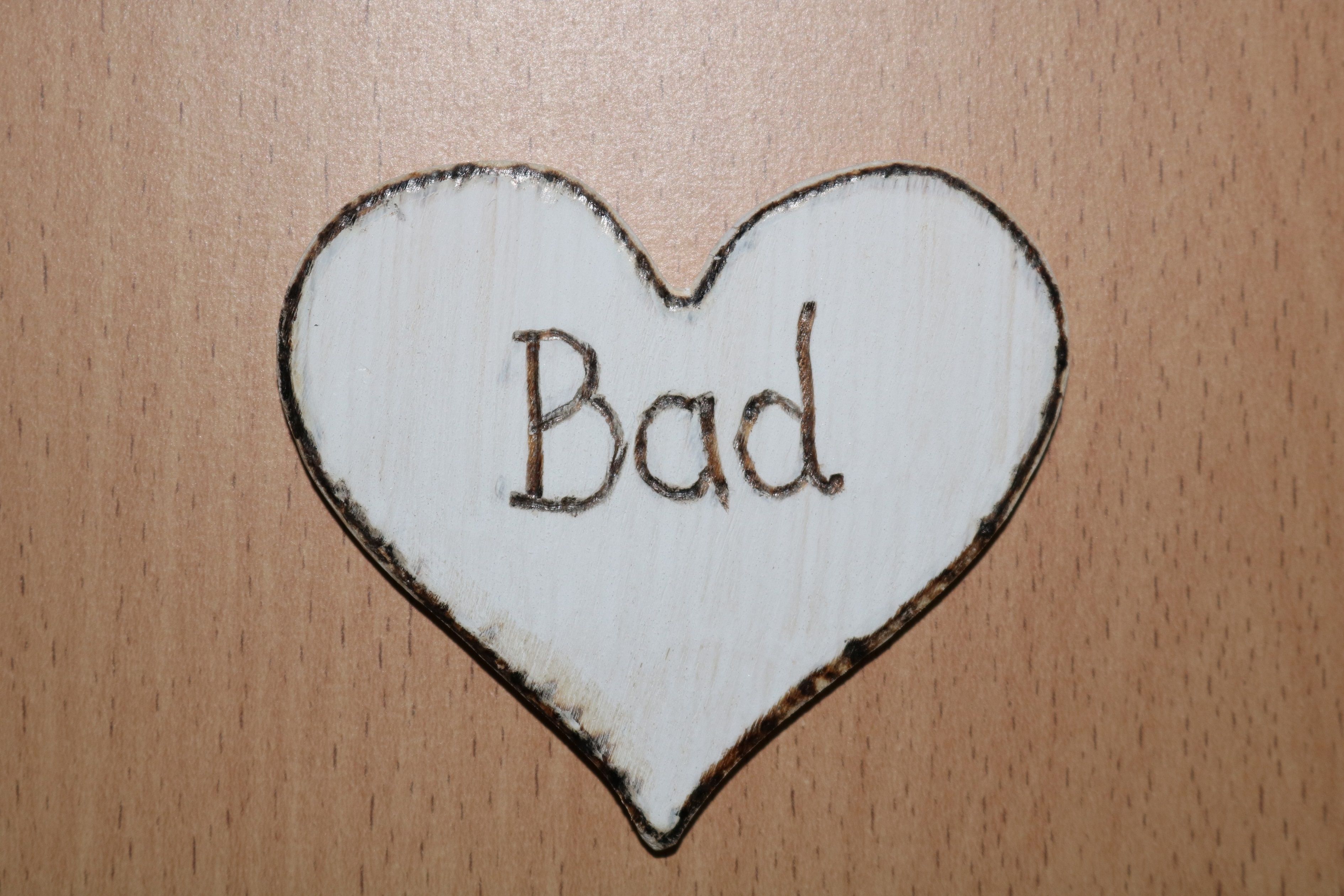 Wooden sign in the shape of a heart with the inscription 'Bad'.