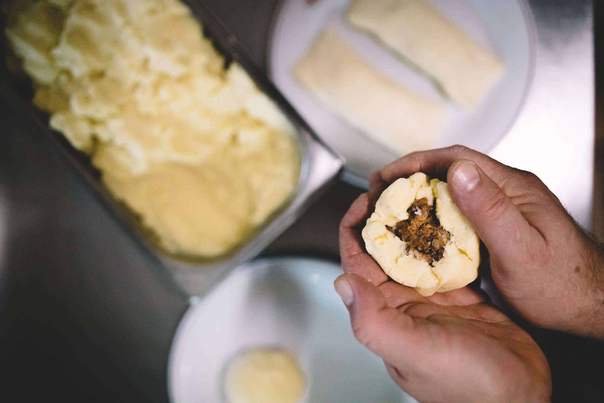 Hands form a filled dumpling from dough.