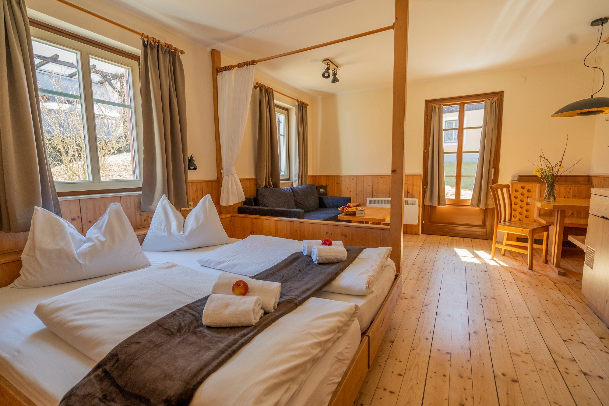 Comfortable room with double bed, sofa, dining table and large windows in the Königsleitn theater and vacation village.