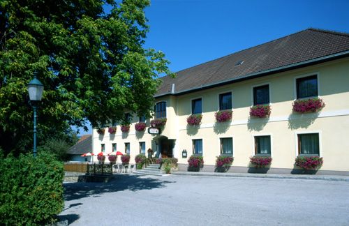 A traditional inn with a yellow façade and flower boxes on the windows.