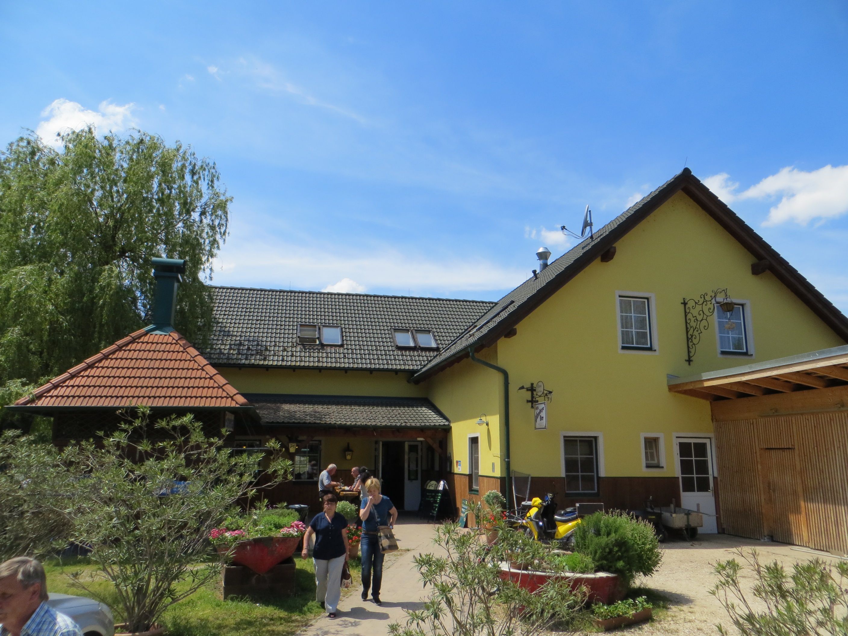 A yellow inn with a gray roof and garden in the foreground.