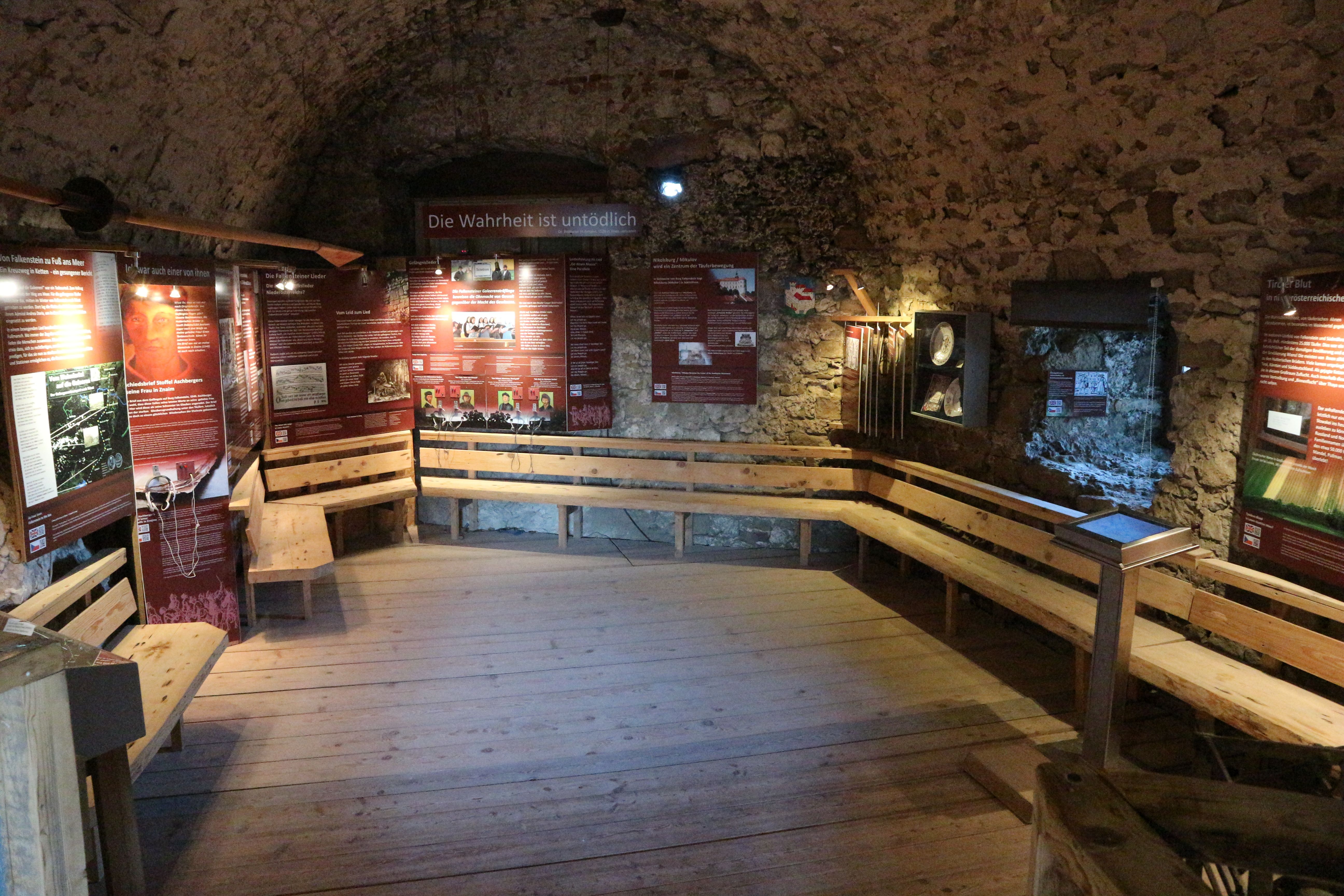 Historical room with information boards and wooden benches.