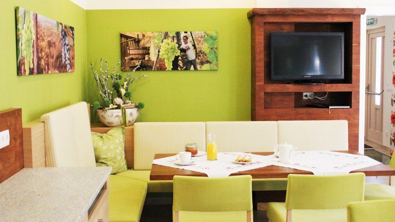 Cozy dining area with green walls, wooden furniture and a TV.