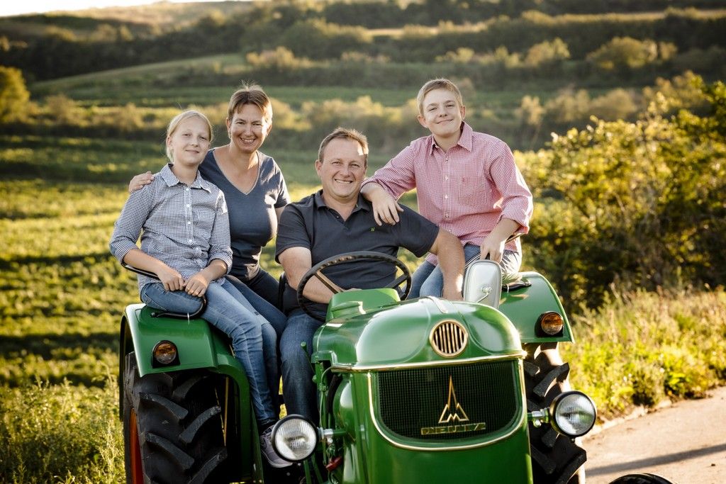 Family on a green tractor in a rural setting.