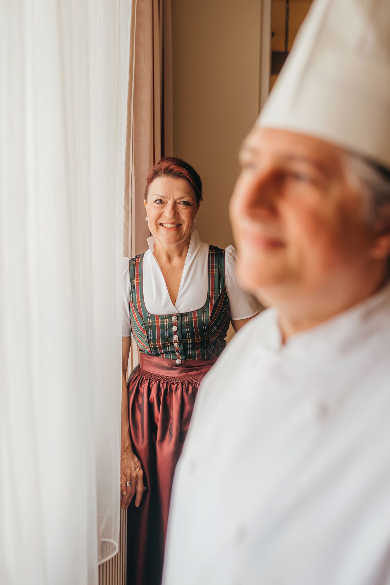 A woman in traditional dress stands next to a cook in a white uniform.