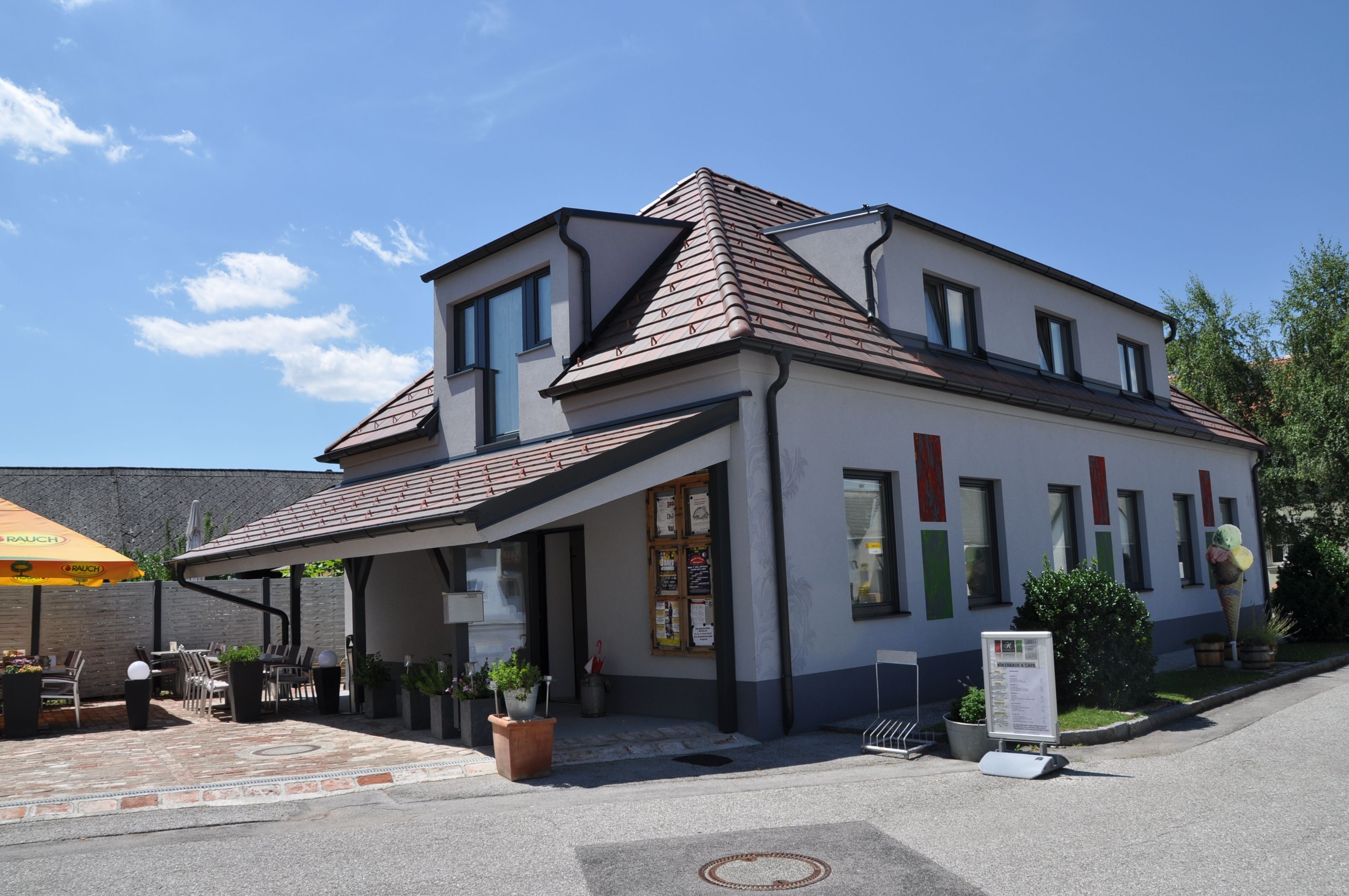 A modern building with a terrace and parasol on a sunny day.