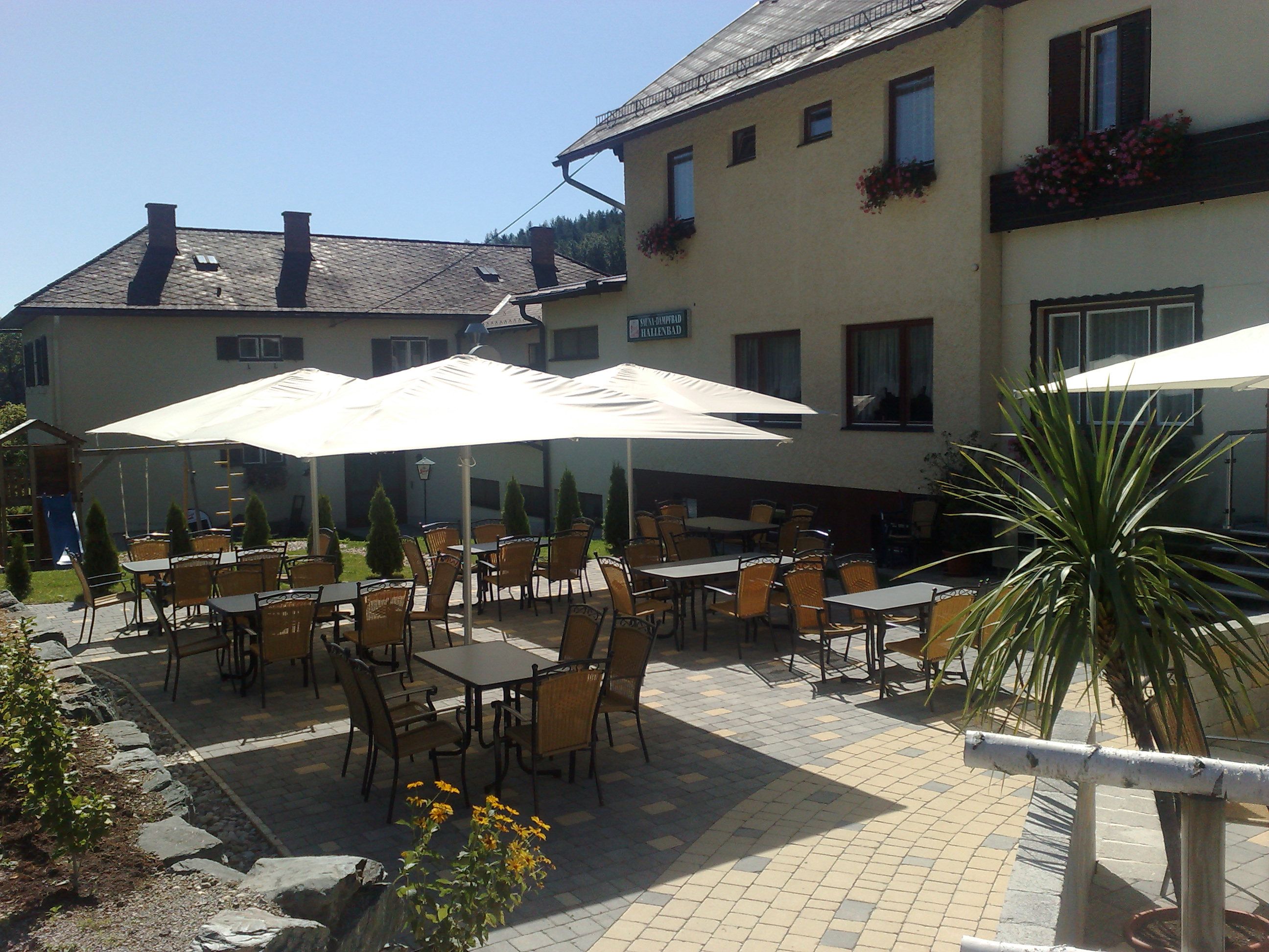 Outdoor area of a guesthouse with tables, chairs and parasols.