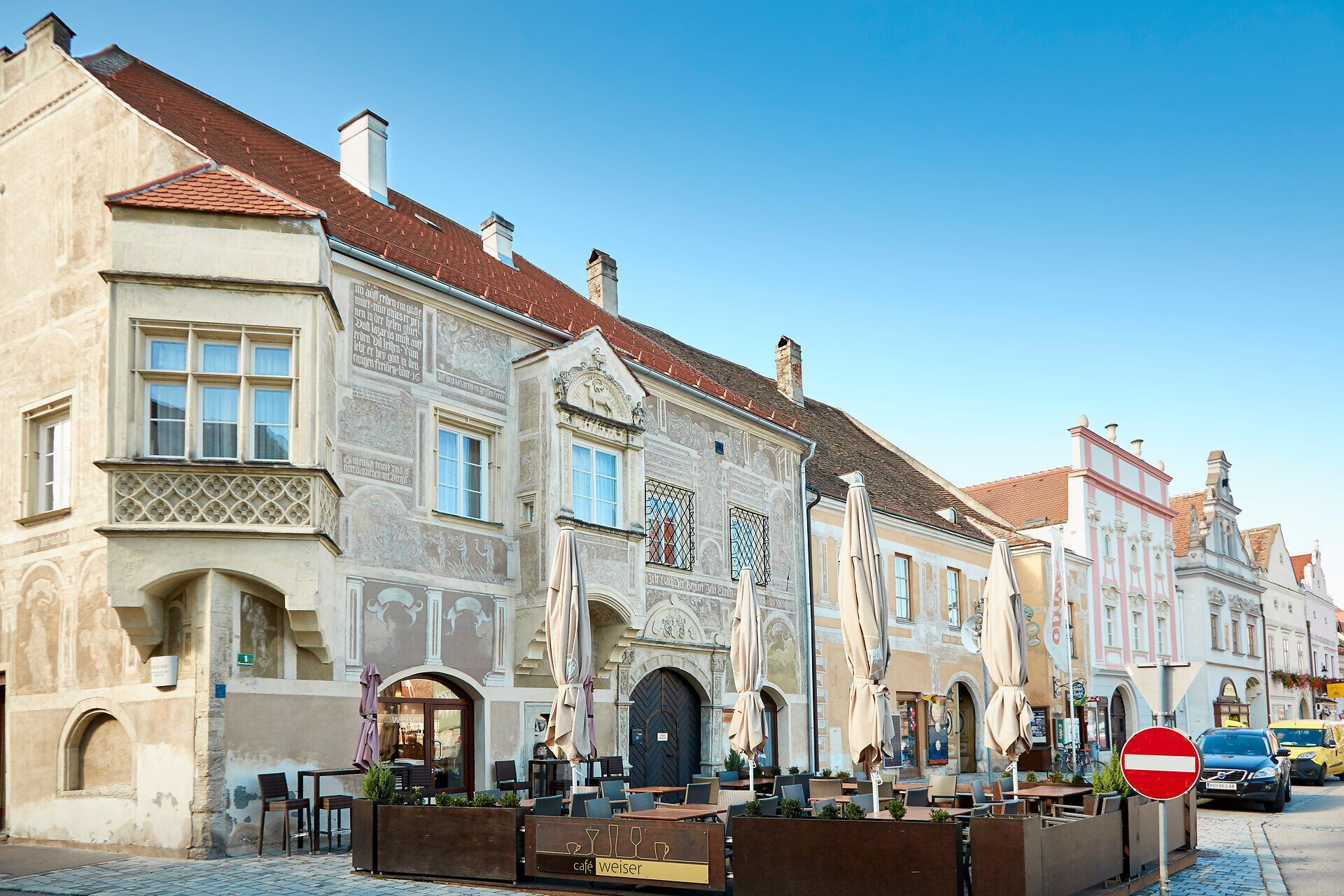 Historic buildings in Eggenburg with ornate facades and a street café in the foreground.