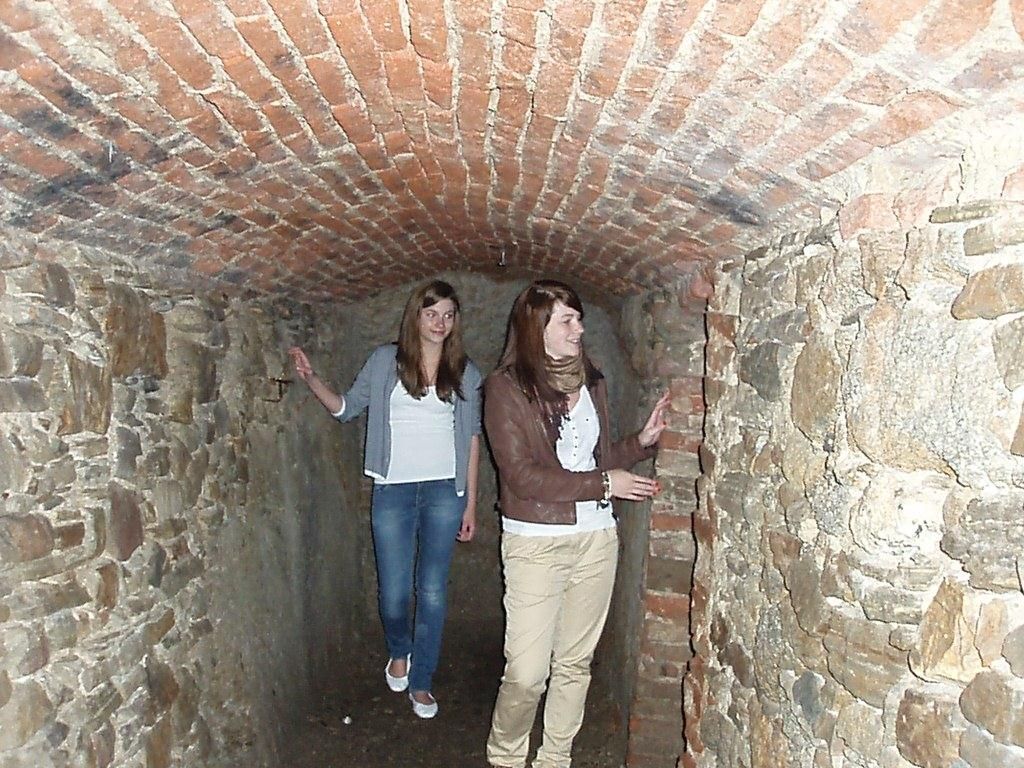 Two women in a narrow, brick-built tunnel with a tiled ceiling.