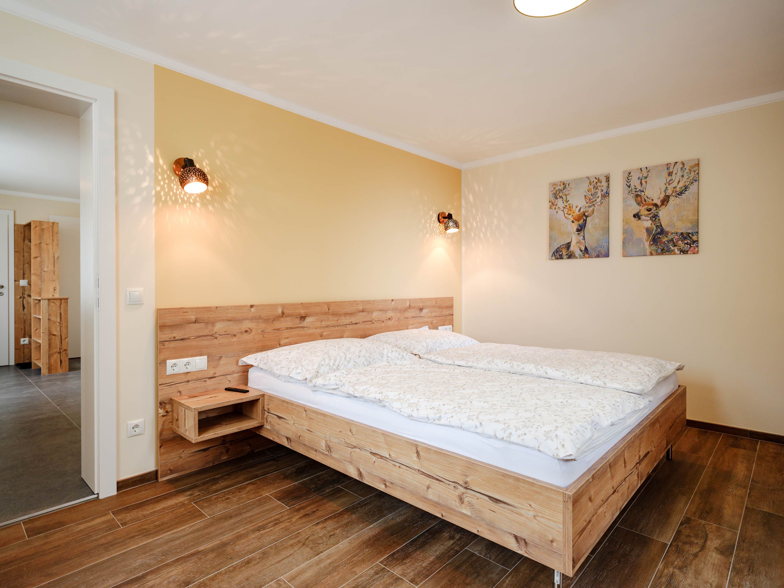 Cozy bedroom with wooden bed and deer pictures on the wall.