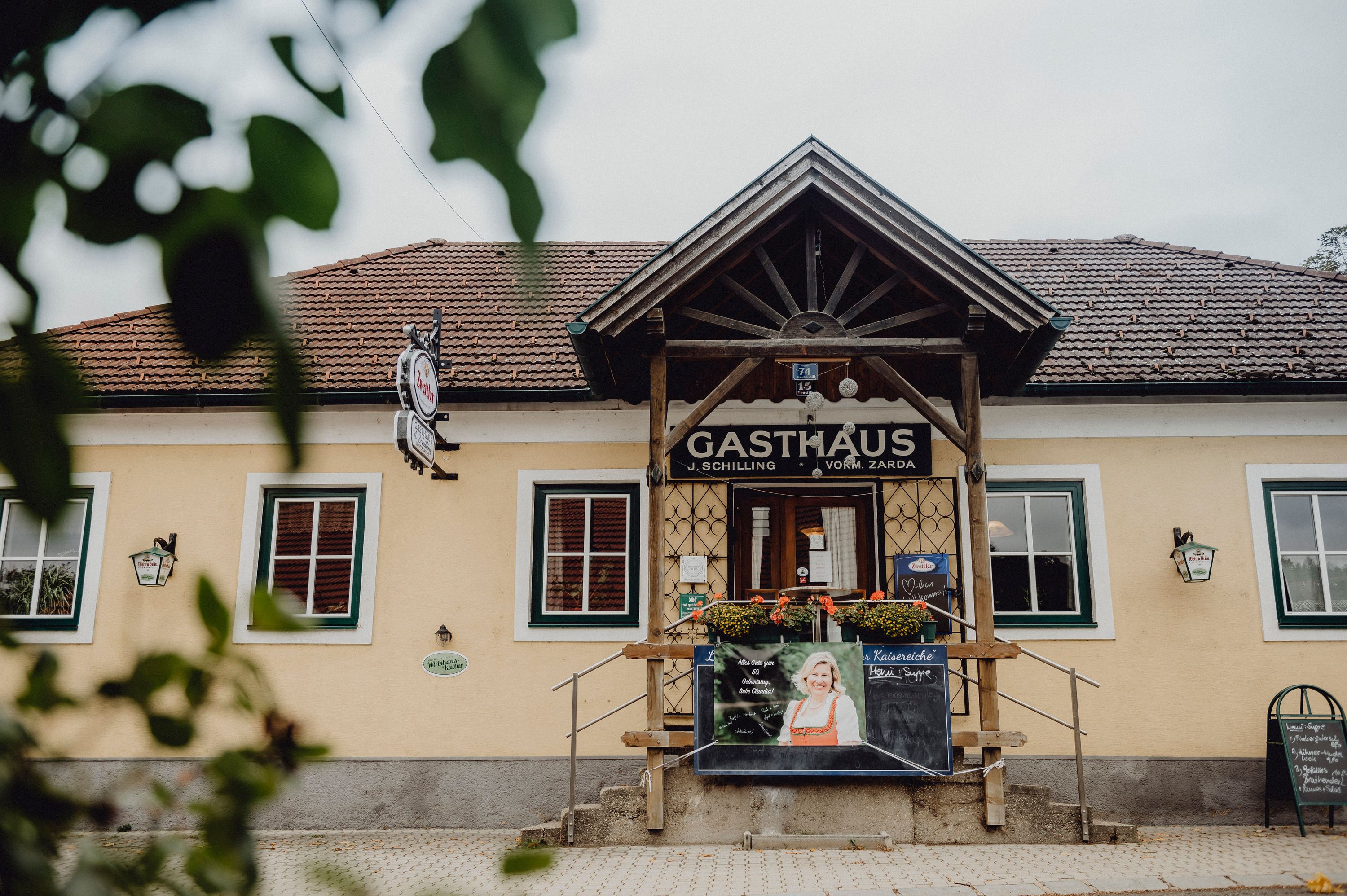 Entrance to a traditional inn with wooden veranda and advertising board.